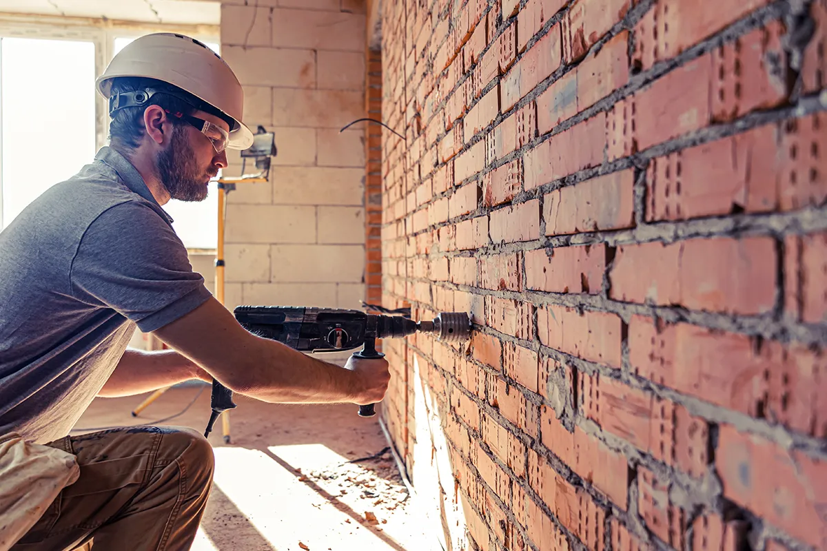 Man filling cracks in a brick wall foundation